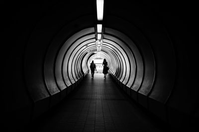 Full length of women walking in illuminated tunnel