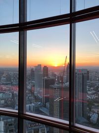 Buildings against sky during sunset seen through glass window