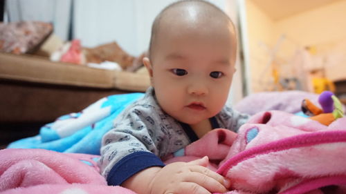 Close-up of baby lying on bed at home