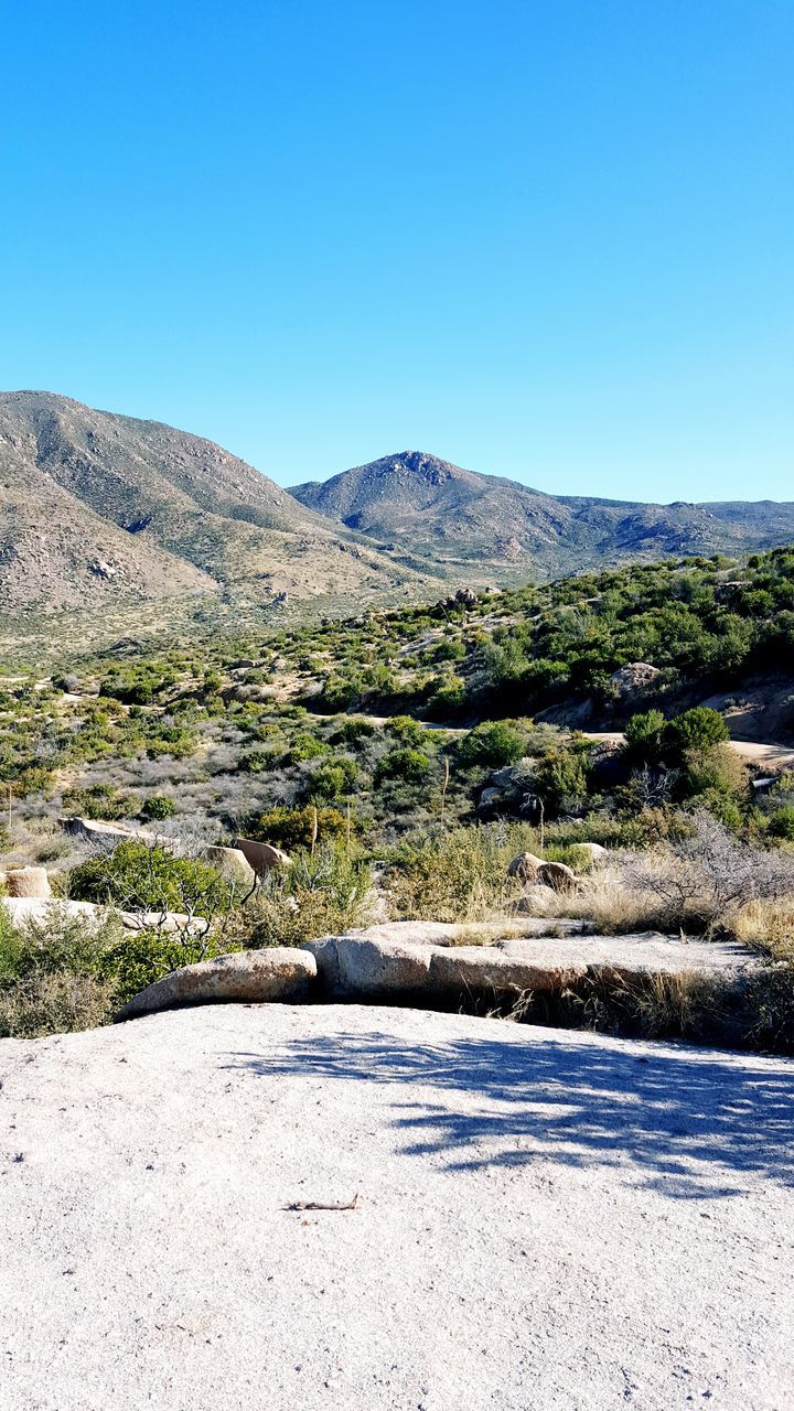 clear sky, mountain, copy space, blue, tranquil scene, mountain range, tranquility, landscape, beauty in nature, scenics, nature, non-urban scene, road, sunlight, day, outdoors, hill, plant, no people, countryside