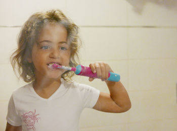 Cute girl brushing teeth in front of mirror