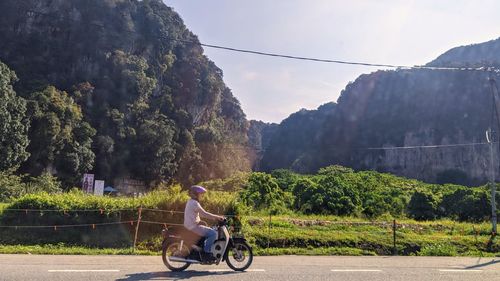 Man riding bicycle on road against trees