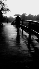 Rear view of silhouette people walking on wet road