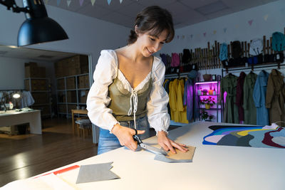 Garment sewing business, young female dressmaker work with textile in workshop for tailoring clothes