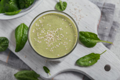 Glass of homemade healthy green smoothie with fresh baby spinach