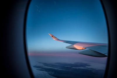 Close-up of airplane wing against clear sky seen through window