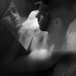 High angle view of sad shirtless man looking at his reflection in mirror