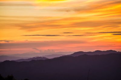 Scenic view of silhouette mountains against orange sky