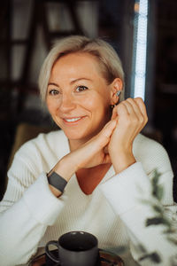 Blond caucasian woman smiling at camera while sitting at table