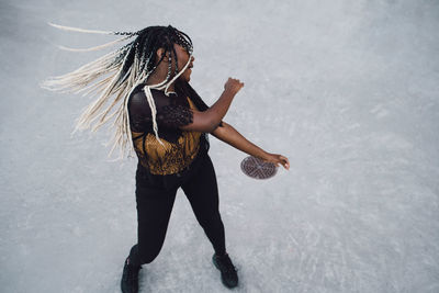 High angle view of teenage girl with tousled dyed hair dancing at skateboard park