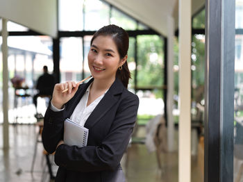 Portrait of smiling young businesswoman standing in office