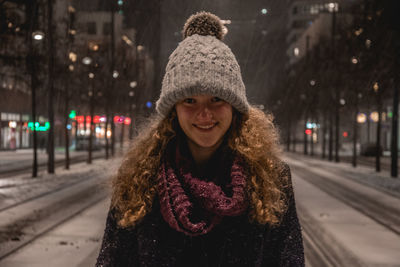 Portrait of smiling young woman standing in city during winter