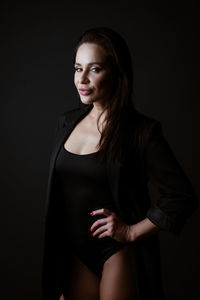 Portrait of woman standing against black background