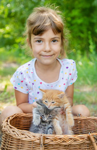 Portrait of cute girl with kittens in basket