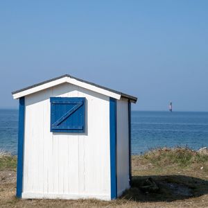 Building by sea against clear blue sky