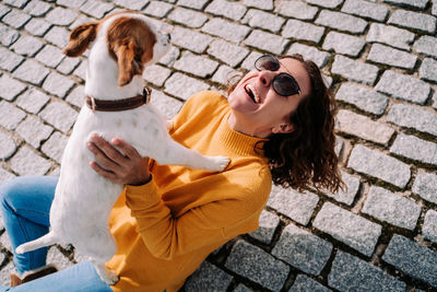 Smiling woman playing with dog outdoors