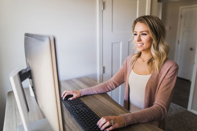 Smiling businesswoman using computer on table at home