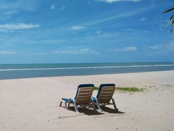 Chairs on beach against sky