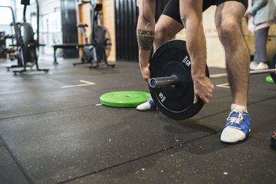 Man picking up barbell while standing in gym