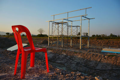 Empty chair on field against clear sky