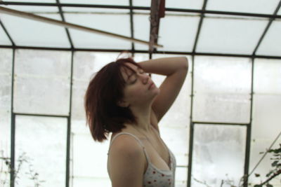Portrait of young woman standing against window