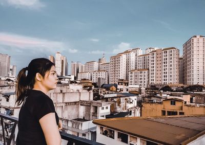 Portrait of woman looking at cityscape against sky