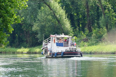 Boat sailing on river amidst trees in forest