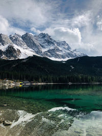 Scenic view of lake by snowcapped mountains against sky