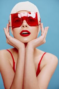 Portrait of woman wearing sunglasses against blue background