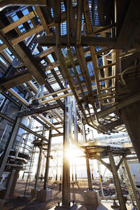 Low angle view of pipelines at power station during sunny day