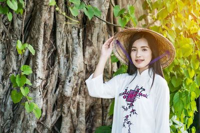 Portrait of smiling young woman standing on tree