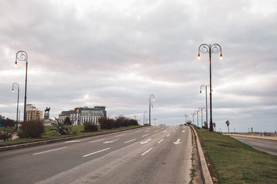 Road sign by street against sky in city