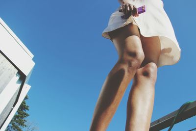 Low angle view of woman standing against blue sky