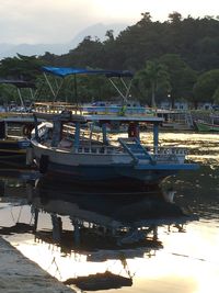 Boats moored at harbor against sky