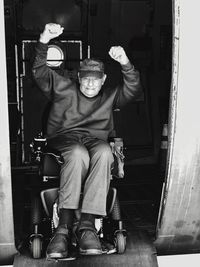 Portrait of excited man sitting wheelchair at doorway on airplane