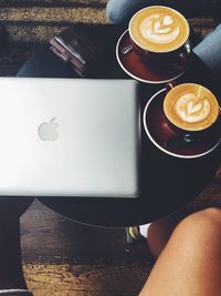 Midsection of people sitting by coffee cup at table