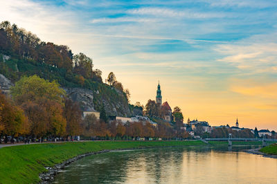 River amidst buildings against sky during sunset