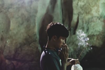 Side view of man with hands clasped praying in temple