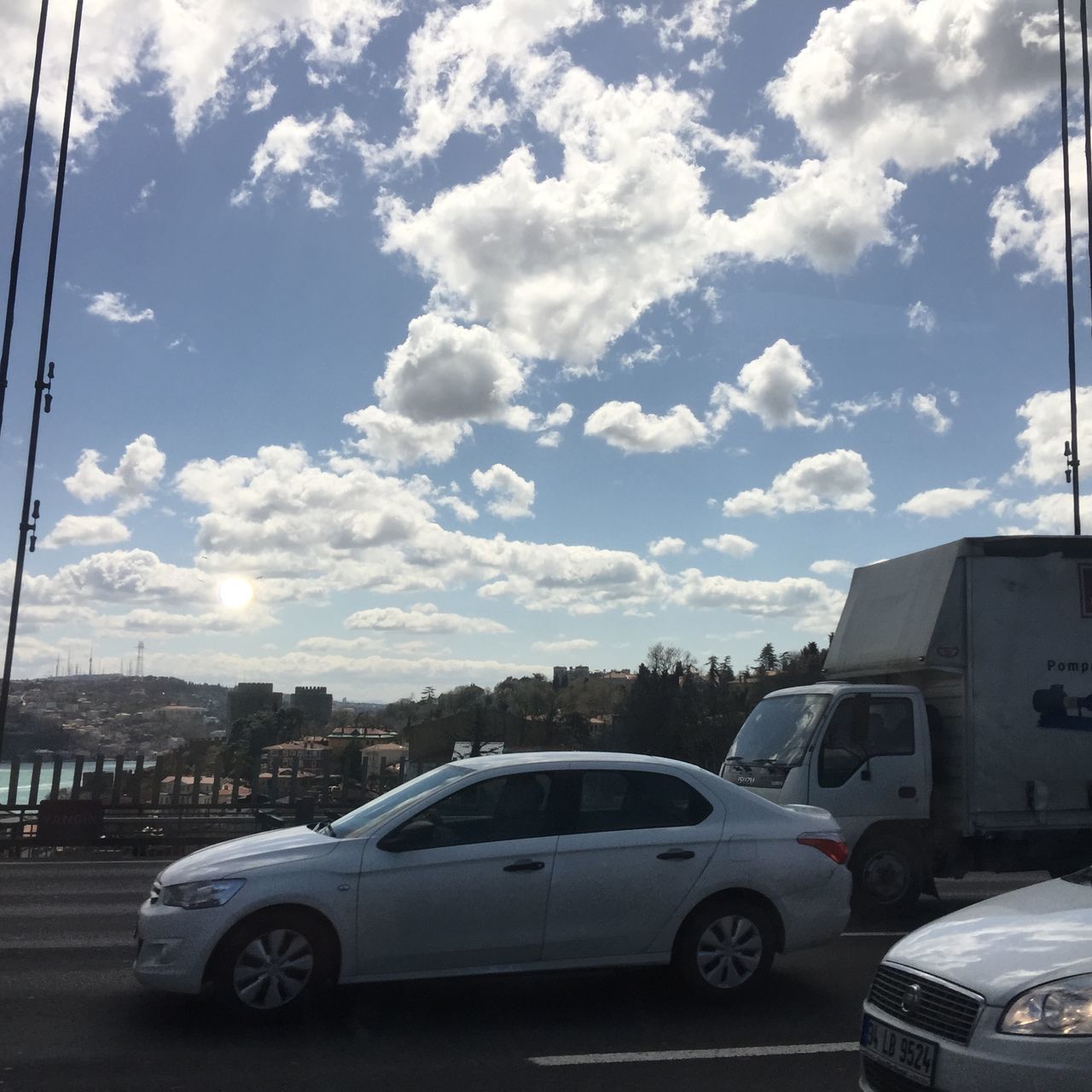 transportation, car, land vehicle, mode of transport, sky, road, street, building exterior, architecture, built structure, cloud - sky, city, vehicle, cloud, parking, stationary, traffic, on the move, day, parked