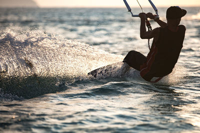 Rear view of man kiteboarding in sea