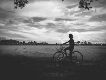 Man riding bicycle on field against sky