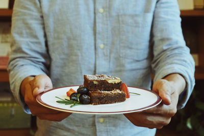 Midsection of man holding pastry in plate