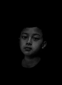 Portrait of boy against black background