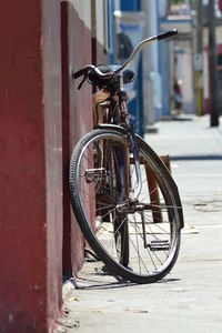 Bicycle parked on sidewalk by wall