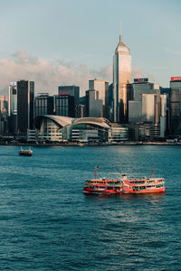 View of city buildings by sea against sky