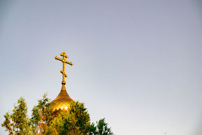 Low angle view of cross against building against clear sky