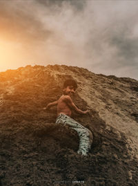 Side view of shirtless man standing on rock