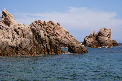 Rock formations in sea against sky