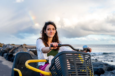 Portrait of woman smiling by sea against sky