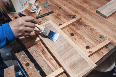 Varnishing a wooden drawer, carpentry workshop. varnish is applied to a wooden board with a brush